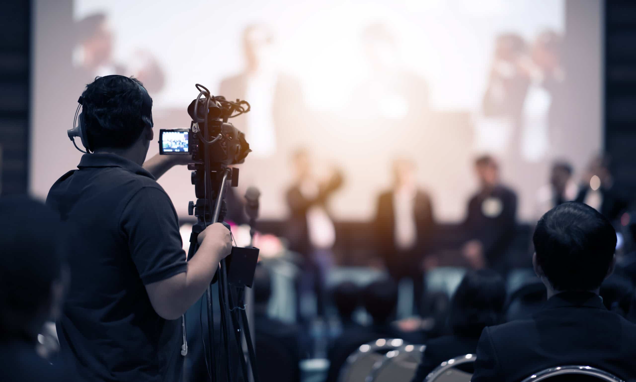 Video camera operator working with his equipment at indoor event